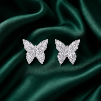 Silver pavé butterfly stud earrings on green satin