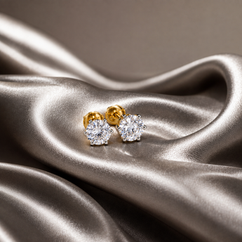 Solitaire round stud earrings with gold screw backs on champagne satin